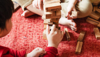 Woman stacking wood blocks representing a named perils or all-risk policy