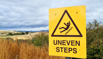 Orange "Uneven Steps" sign representing legal liability