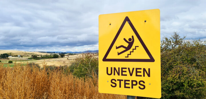 Orange "Uneven Steps" sign representing legal liability
